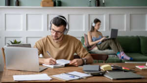 Dos personas en una casa trabajando y estudiando desde sus propios computadores portátiles.