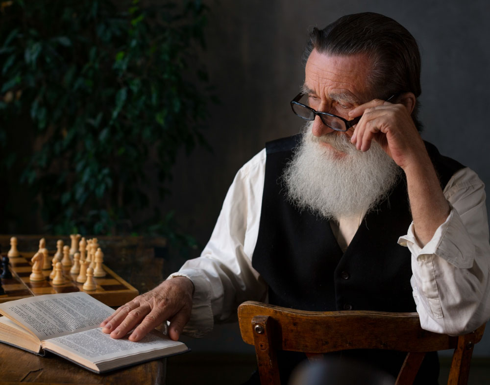 Hombre con barba y gafas escribiendo en un computador portátil.