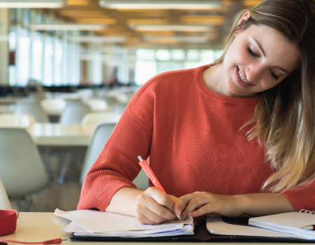 Mujer escribiendo en una libreta de apuntes.
