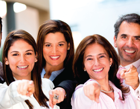 Grupo de personas señalando y sonriendo a la cámara.