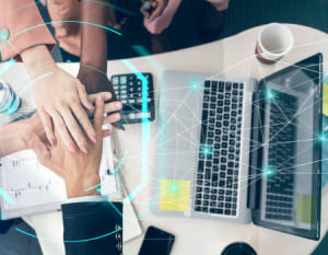 Equipo administrativo con las manos unidas cerca a un computador portátil.