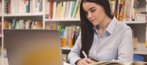 Investigadora con un computador portátil y algunos libros.