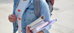 Torso de estudiante que lleva consigo unos cuadernos.