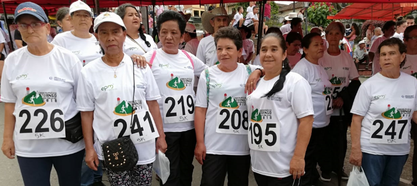 Mujeres mayores, vestidas de camisetas blancas, se preparan para carrera atlética.
