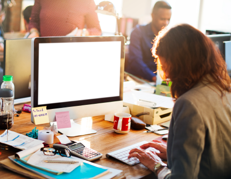 Mujer trabajando en una oficina al frente de un computador.