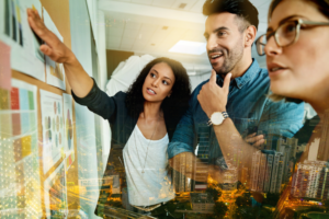 Tres personas en un ambiente de negocios observando gráficos en un tablero.