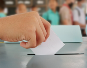 Persona emitiendo su voto en una urna.