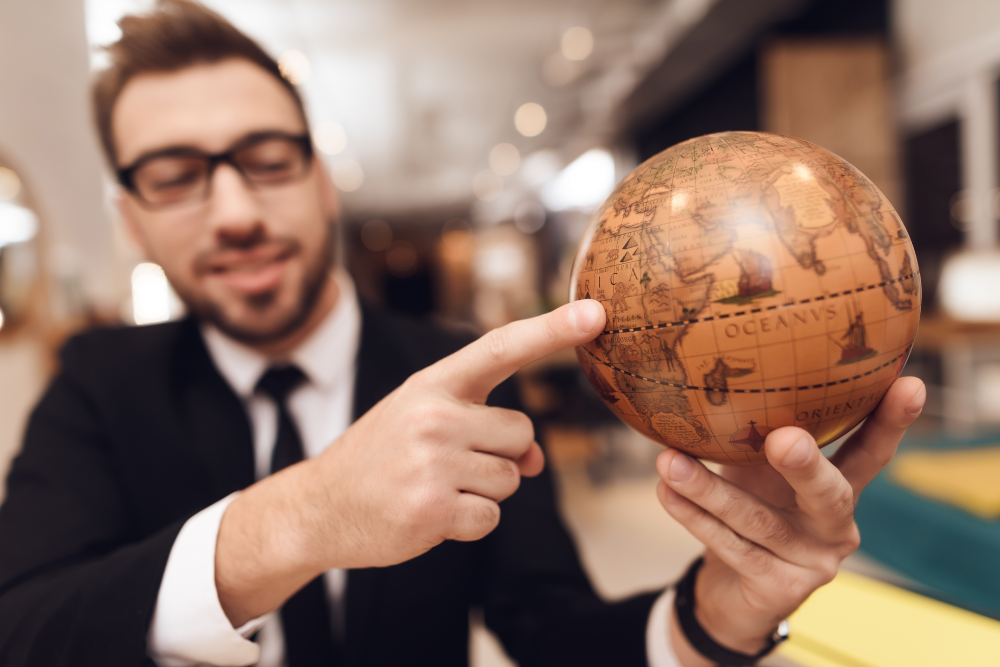 Hombre sosteniendo un globo terráqueo y apuntando con su índica el continente africano.