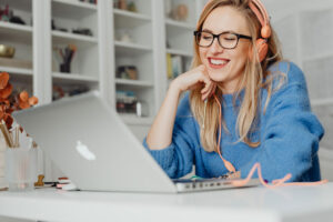 Mujer sentada frente a un computador portátil apoya su cabeza sobre el puño de su mano derecha.