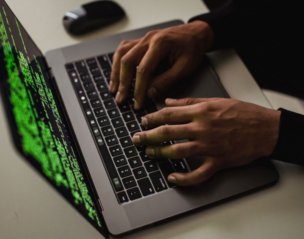 Persona escribiendo en el teclado de un computador portátil.