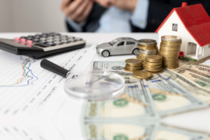 Dinero, calculadora, carro de juguete y una lupa sobre una mesa.