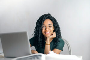 Mujer sonriente sentada cerca a computador portátil.
