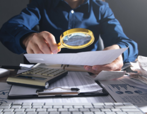 Hombre con una lupa registra estados contables en un ambiente corporativo.