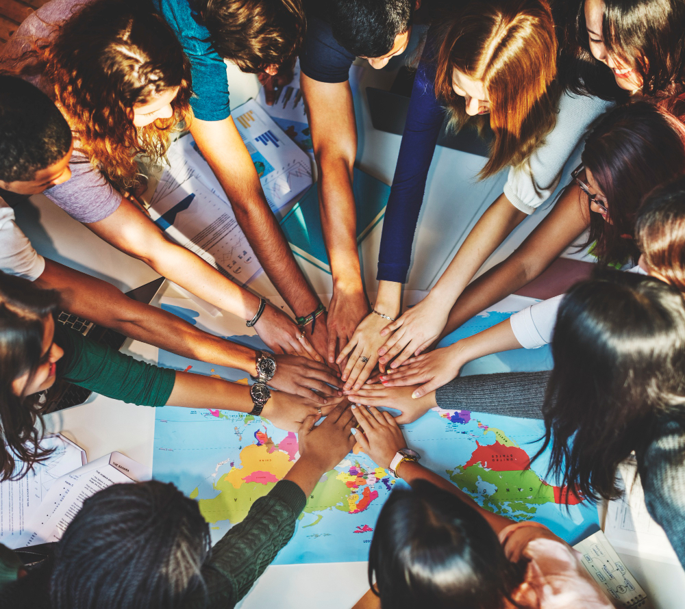 Personas juntando las manos, debajo un mapa mundial