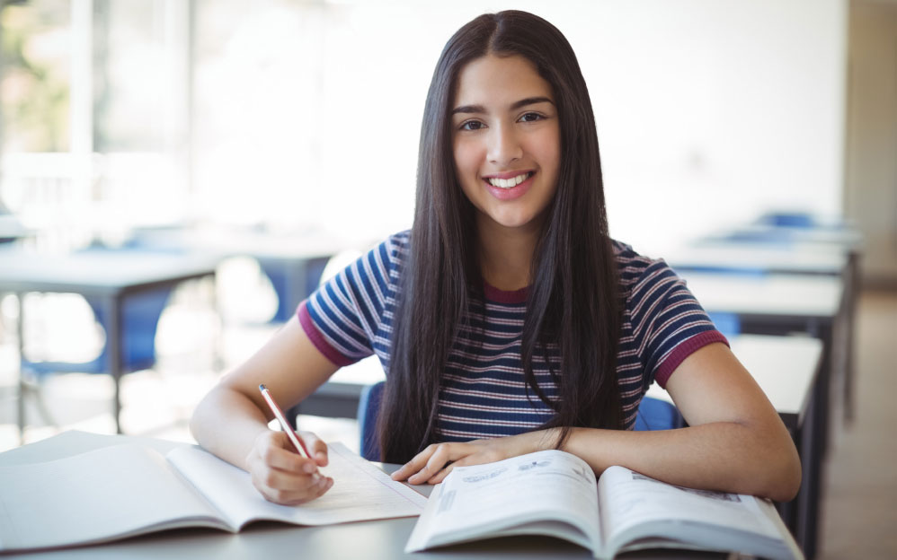 Mujer joven estudiante con libros y un lápiz.